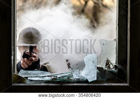 Photo Of A Solder Pointing A Gun Trough A Window While There Is Fog Outside