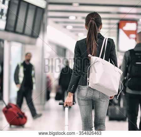 Travel background airport terminal passengers walking in lounge. Asian woman walking from behind with purse carrying luggages for delayed flights to vacation holidays.