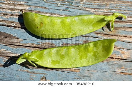 Erbsen frisch aus dem Garten auf einem rustikalen Tisch.