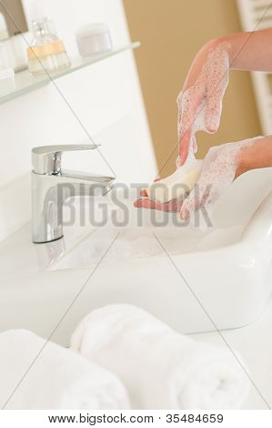Primer plano de lavarse las manos con jabón sobre el lavabo del baño