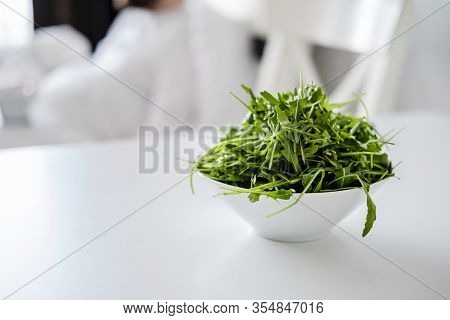 Fresh Arugula Or Rocket, Eruca Vesicaria, In A Plate, On A White Table, In Natural Light. Concept Of