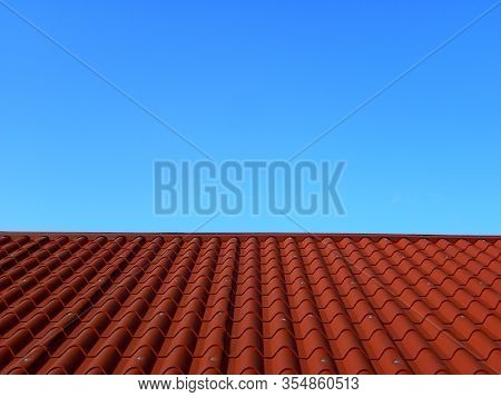 Red Tile Roof Under Blue Sky. The Photo Is Divided In Half. One Part Is A Roof Made Of Clay Tiles An