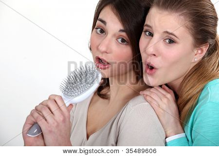 Due ragazza cantando in spazzola per capelli