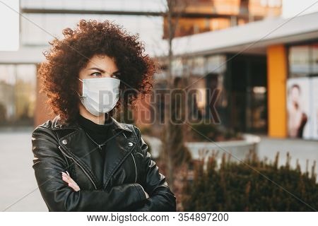 Caucasian Lady With Curly Hair Is Posing With Crossed Hands While Wearing An Anti Virus Mask