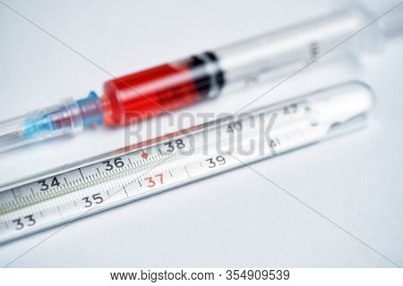 Thermometer On A White Background Syringe With Red Medicine For Lowering Temperature. Close Up.