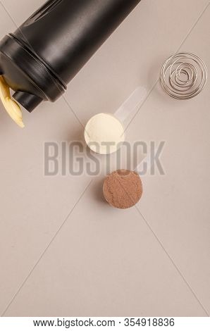 Whey Protein Powder In Scoop And Plastic Shaker On Neutral Beige Background