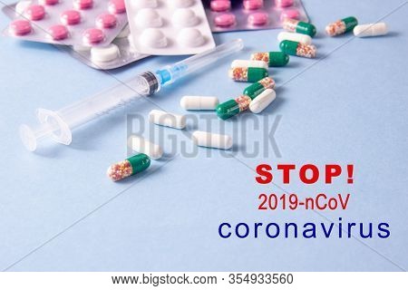 Coronavirus Phrase Text On A Blue Background With Medicines And A Syringe. The Concept Of The New 20