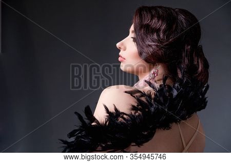 Beautiful Brunette  Woman In Boa From Ostrich Feathers Sits In Front Of The Camera With His Back And