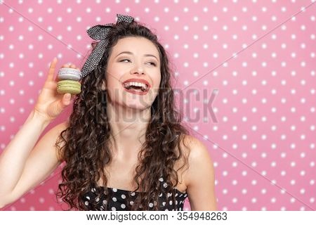 Full Of Energy Kinky Girl Is Holding Two Macaroons, Looking To The Side And Laughing Desparately.