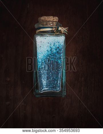 Fancy Bottle With Blue Bath Salts For Relaxing Spa Treatments With Wooden Background