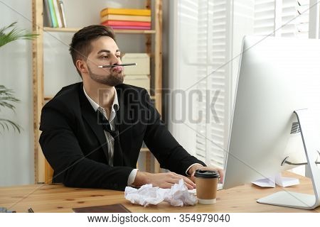 Lazy Employee Playing With Pencil At Table In Office