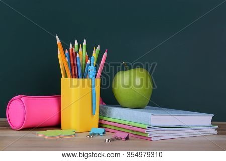 Composition With Stationery And Apple On Table Near Chalkboard. Doing Homework