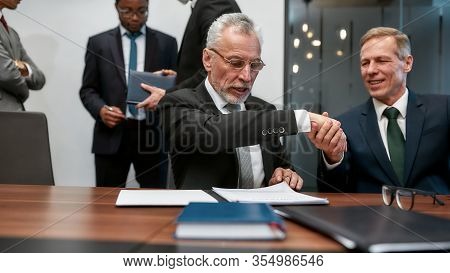 Two Happy Mature Businessmen In Classic Wear Shaking Hands After Contract Signature While Having A M