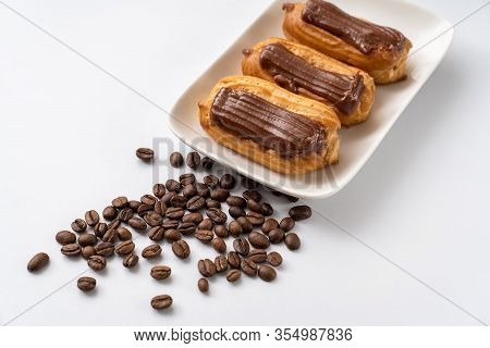 Copy Space. Fragment Plate Custard Cakes With Chocolate Icing And Coffee On A White Background.