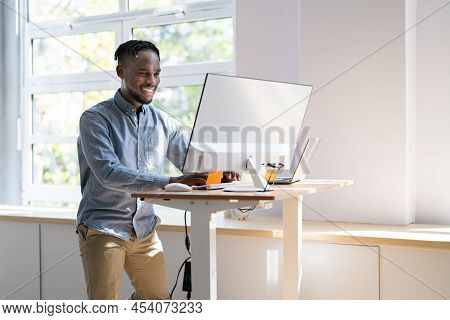 Man Using Adjustable Height Standing Desk In Office For Good Posture