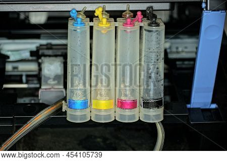 A Row Of White Empty Plastic Bottles For Paints Stand On A Black Printer