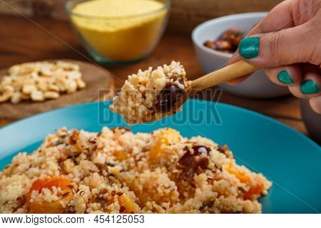 A Plate Of Couscous On A Wooden Table Next To Dates, Nuts And A Jug Of Fruit Broth, A Spoon With Cer
