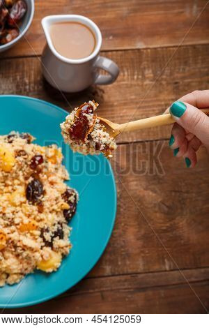 A Plate Of Couscous With Dried Fruits And Nuts On A Wooden Table Next To The Ingredients. Vertical P