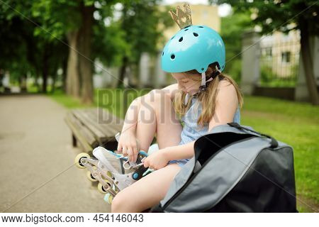 Young Girl Putting On Her Inline Roller Skates On Beautiful Summer Day In A Park. Child Enjoying Rol