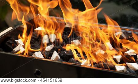 Empty Barbecue Flaming Grill Close Up With Bright Flames And White Firelighters Burning
