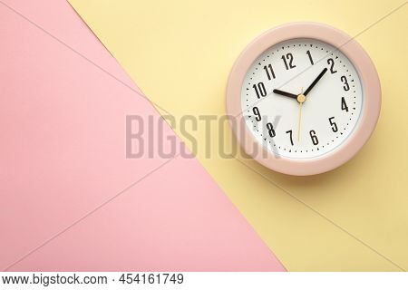 Pink Clock On Beige And Pink Background. Top View. Space For Text