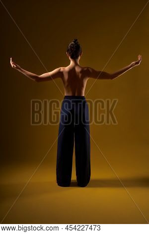 Back View Of Brunette With Hair Bun Doing Yoga At Studio, Flexible Woman Standing With Bare Back. Ra