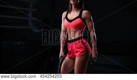Athletic Woman In Red Shorts And Top Exercising With Ropes In Functional Training Area. Fitness Conc