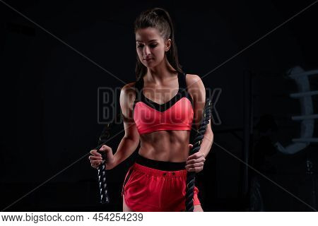 Athletic Woman In Red Shorts And Top Exercising With Ropes In Functional Training Area. Fitness Conc