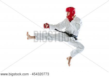 Portrait Of Young Sportive Man Wearing White Dobok, Helmet And Gloves Practicing Isolated Over White