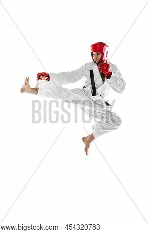 Portrait Of Young Sportive Man Wearing White Dobok, Helmet And Gloves Practicing Isolated Over White