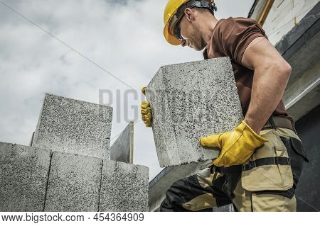 Hollow Dense Concrete Blocks Moved By Caucasian Construction Contractor Worker. Residential Construc