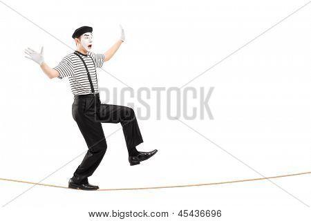 ความยาวเต็มภาพเหมือนของศิลปินแบบ mime ชายตื่นเต้นเดินบนเชือก แยกต่างหากบนพื้นหลังสีขาว