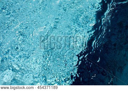 Blue Water Surface In The Swimming Pool With Ripples And Light Sparkles