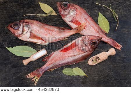 Raw Carcasses Of Redfish And Spices On The Black Surface