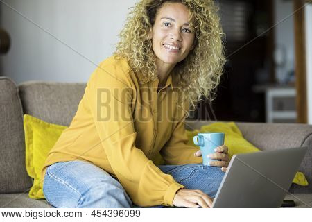 Young Woman Smile And Work On Laptop At Home Sitting On The Sofa. Happy Adult Female People Using Co