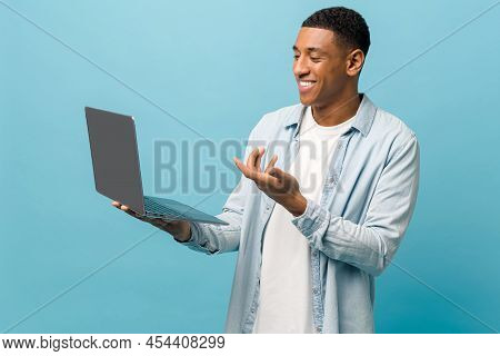 Handsome Happy African-american Male Student In Casual Jeans Shirt Using Laptop Pc For Video Call Is