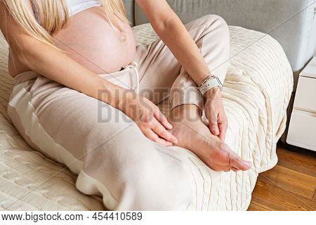 Pregnant Woman With Naked Belly At Home Massaging Tired Painful And Spider Varicose Veins. Healthcar