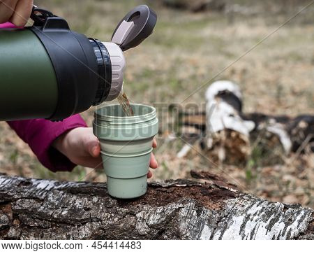 Woman Hands Pouring Tea From Thermos Into Mug On Nature Background. Pitstop On Trail In Autumn Or Sp