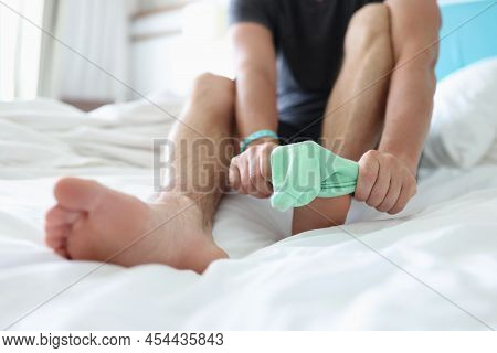 Close-up Of Man Try To Pull Sock On Foot, Dress Up To Go Out, Sit On Bed For Comfort. Bright Green S