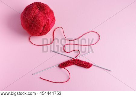 Red Knitted Wool On A Pink Background With Knitting Needles, Hobby