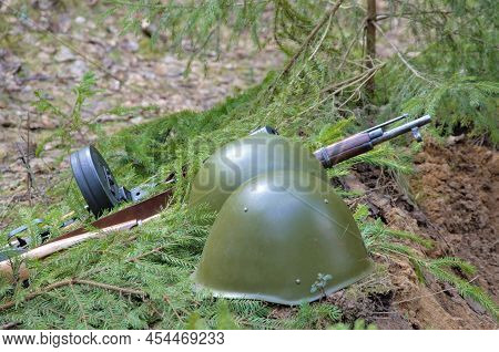 A Wartime Helmet And A Machine Gun Lie On The Edge Of The Trench