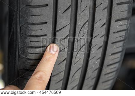 Mechanic Pointing With Hand At Tyre Wear Indicator At Car Service Center. Vehicle Wheel Protector Co