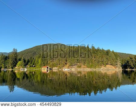 Perfect Reflection Of A Small Hill In Bargain Bay, Near Pender Harbour, British Columbia, Canada