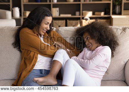 African Girl Her Mother Tickling Each Other Seated On Sofa