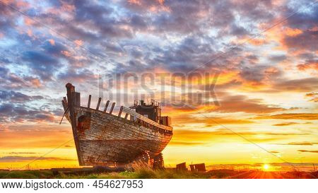 An Old Wooden Boat At Seashore And Sun Set In East. In Behind Of Boat Yellow Dark White And Differen