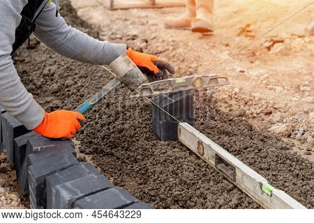 Builder Installing Paving Blocks During Road And Footpath Construction On Semi-dray Concrete Mix