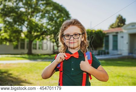 Cheerful Little School Boy In School Uniform With Backpack Standing Near School. Back To School. Kid