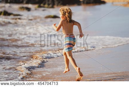 Child Running Through Water Close To Shore Along The Sea Beach. A Boy Runs Along The Sea Coast. Rest