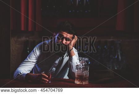 Drunk Man Sitting At The Counter In A Pub Or A Bar And Drinking Cognac Or Whiskey. Scotch And Cognac