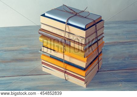 Vertical Stack Of Books Tied With Rope On Rustic Table.  Free Space For Text
